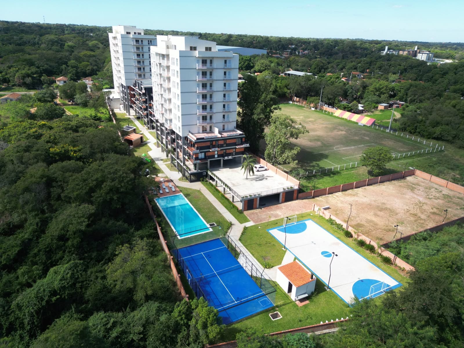 Vista aérea del resort urbano con piscina y canchas